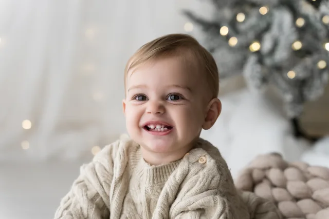 Primo piano di un bambino biondo che ride nel set di Natale
