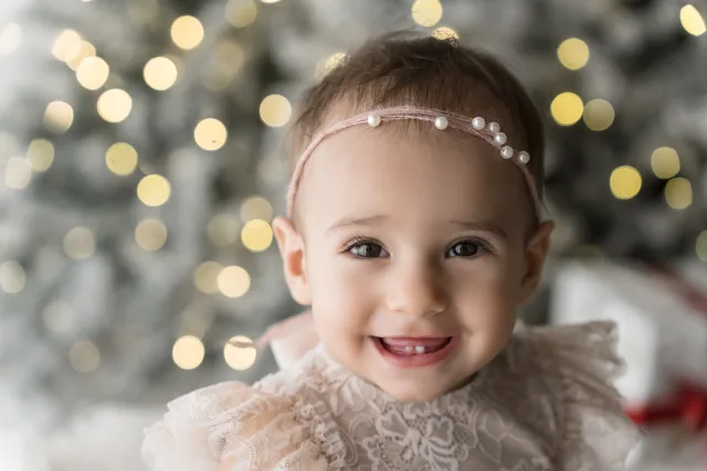 Bambina con la coroncina di perline davanti all’albero illuminato