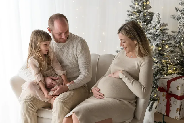 Famiglia con la mamma in attesa e la bambina nel set natalizio