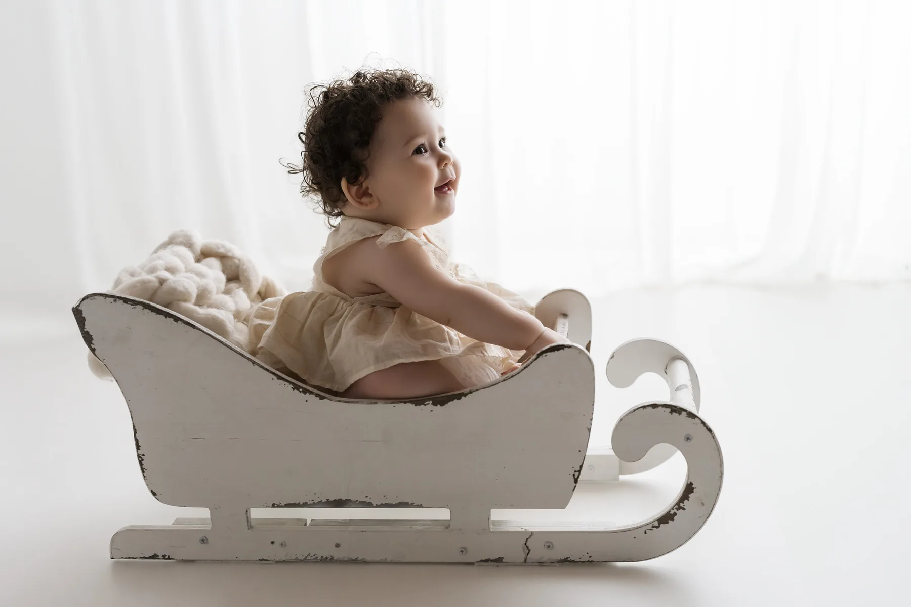 Bambino seduto nella slitta di legno del set natalizio dell'Atelier di Livorno