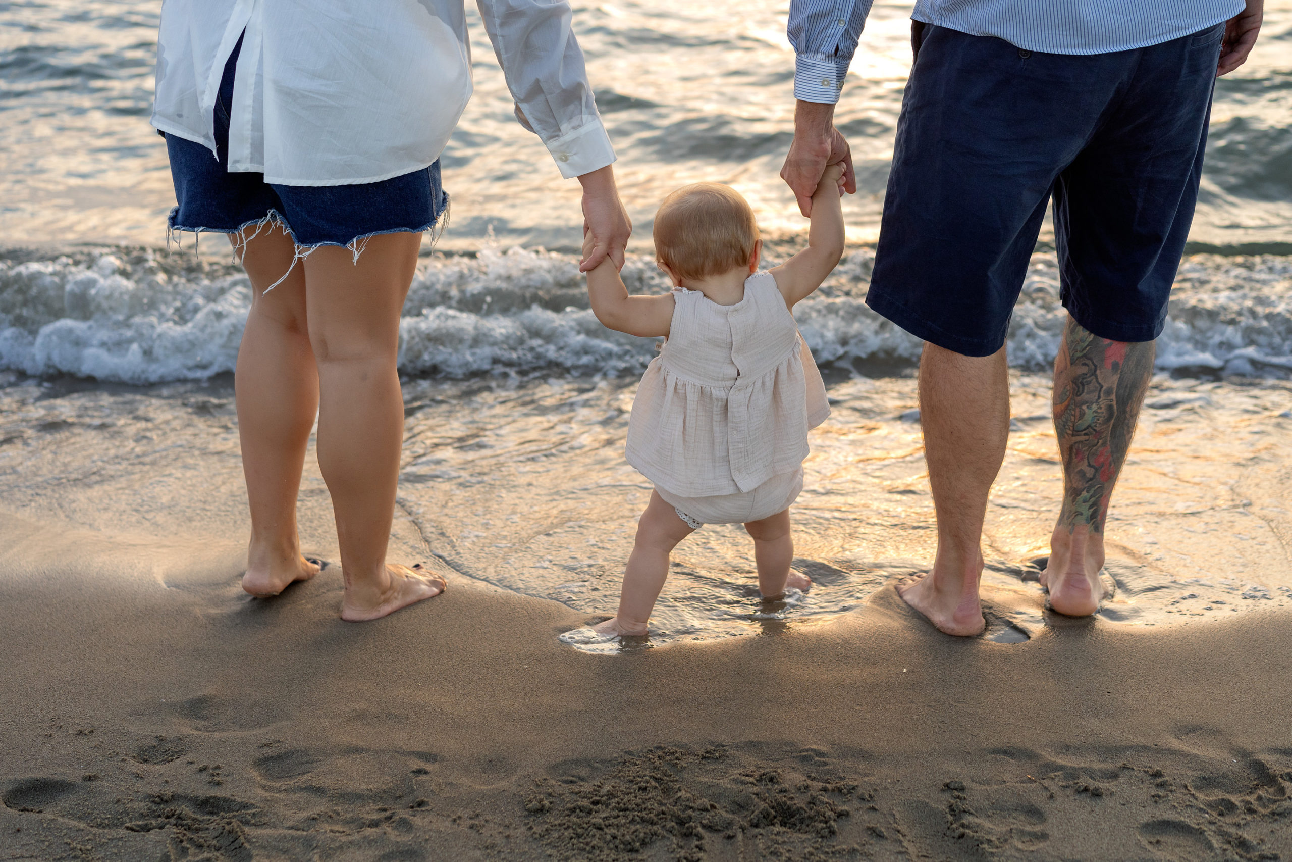 estate, fotografia di famiglia, famiglia di spalle in riva al mare, a piedi nudi nell'acqua